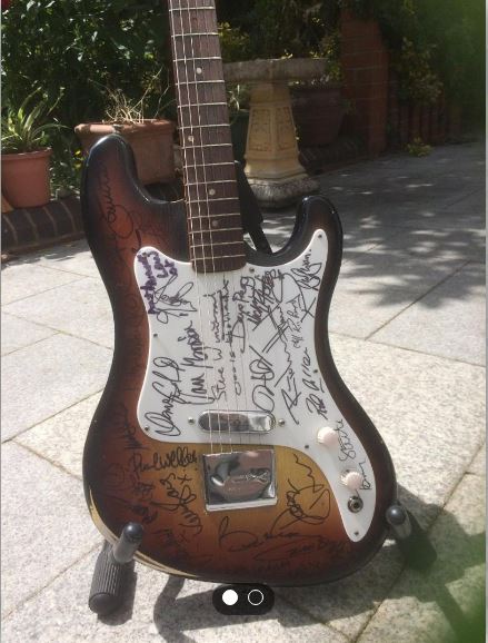 Tony signs a vintage Vox guitar for MacMillan Cancer Charity